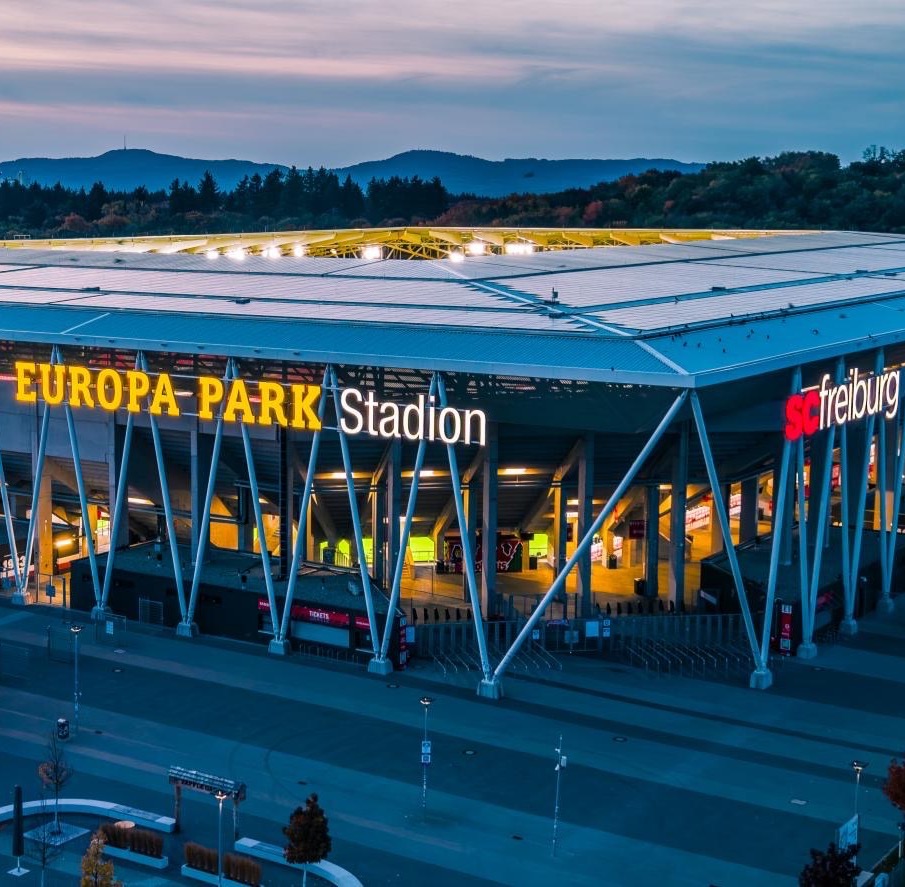Das Europa-Park Stadion in Freiburg in der Abenddämmerung, die Schriftzüge Europa-Park Stadion und SC Freiburg sind beleuchtet